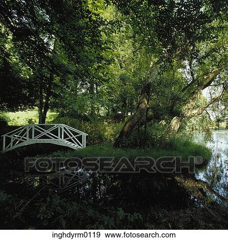 A white bridge over a small pond in a garden View Large Photo Image Stock Photo - A white bridge over a small pond in a garden. Fotosearch