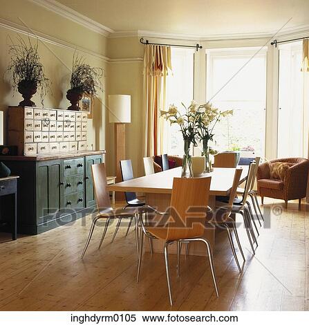 Stock Photography - A wooden dining table with chairs in a dining room with French windows. Fotosearch