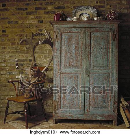 An antique wooden cupboard next to a moose head on a chair View Large Photo Image Stock Photo - An antique wooden cupboard next to a moose head on a chair. Fotosearch