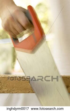 Close-up of a man's hand using a hand saw on a piece of wood View Large Photo Image Stock Photo - Close-up of a man's hand using a hand saw on a piece of wood. Fotosearch