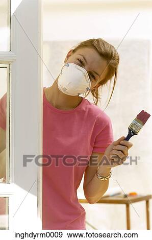 Close-up of a young woman wearing a protective mask and holding a paintbrush View Large Photo Image Stock Photo - Close-up of a young woman wearing a protective mask and holding a paintbrush. Fotosearch