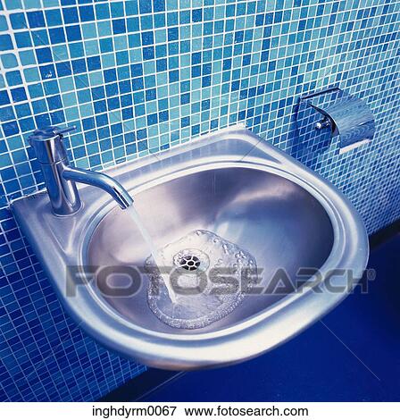 Stock Photo - High angle view of a running tap in a bathroom basin. Fotosearch