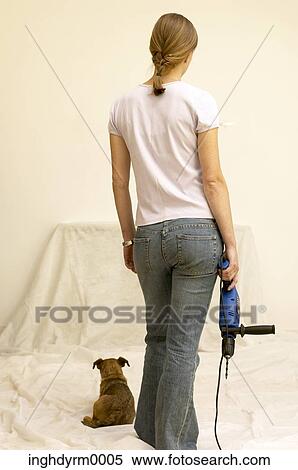Stock Photography - Rear view of a young woman holding an electric drill machine. Fotosearch