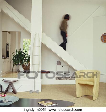 Side profile of a young woman walking down a flight of stairs in a living room View Large Photo Image Stock Image - Side profile of a young woman walking down a flight of stairs in a living room. Fotosearch