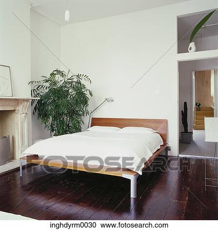 View of a bedroom with wooden floors and a potted plant View Large Photo Image Stock Image - View of a bedroom with wooden floors and a potted plant. Fotosearch
