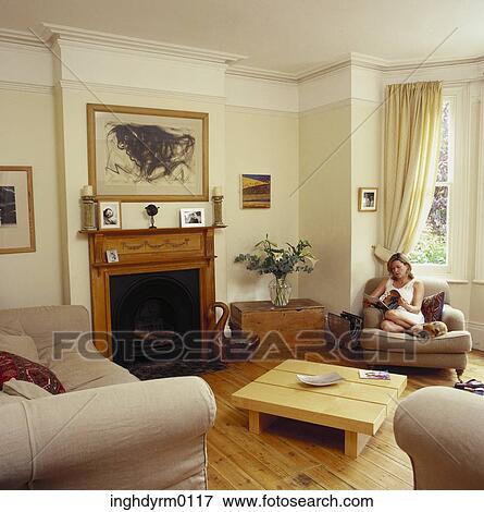 Woman sitting on a couch in a living room reading a magazine View Large Photo Image Stock Photo - Woman sitting on a couch in a living room reading a magazine. Fotosearch