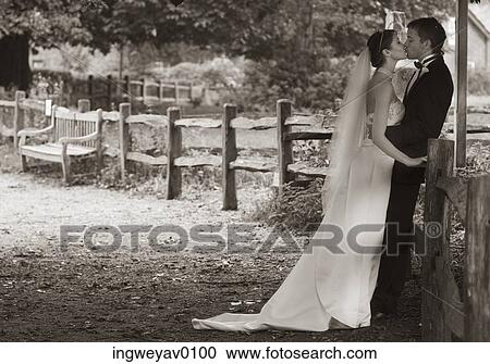 A newly married couple kissing against a fence View Large Photo Image Stock Image - A newly married couple kissing against a fence. Fotosearch