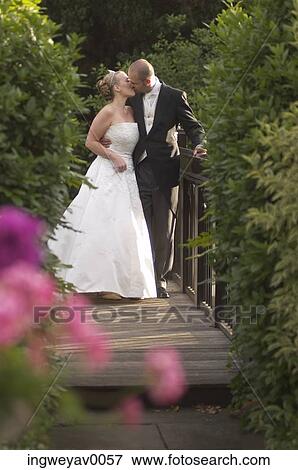 A newly married couple kissing on a wooden bridge View Large Photo Image Stock Photo - A newly married couple kissing on a wooden bridge. Fotosearch