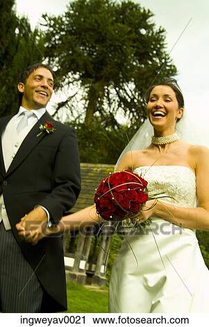 A newly married couple walking in a garden View Large Photo Image Stock Image - A newly married couple walking in a garden. Fotosearch