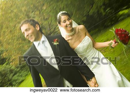 A newly married couple walking in a garden View Large Photo Image Stock Image - A newly married couple walking in a garden. Fotosearch
