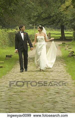 A newly married couple walking on a trail in a garden View Large Photo Image Stock Photo - A newly married couple walking on a trail in a garden. Fotosearch