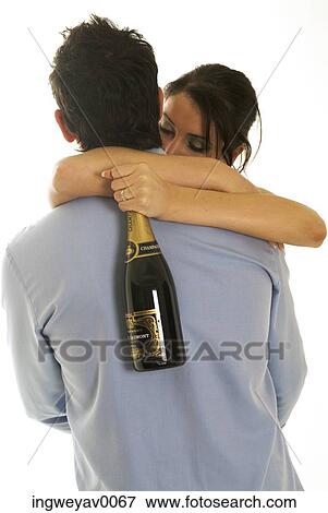 A young woman hugging a man with a champagne bottle in hand View Large Photo Image Stock Photo - A young woman hugging a man with a champagne bottle in hand. Fotosearch