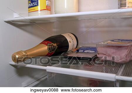 Stock Photo - Bottle of champagne and ham inside of a refrigerator. Fotosearch