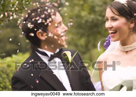 Stock Photo - Close-up of a young bride and groom under falling confetti. Fotosearch