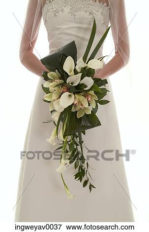 Close-up of a young bride holding a bouquet of flowers View Large Photo Image Stock Photo - Close-up of a young bride holding a bouquet of flowers. Fotosearch