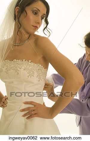 Close-up of a young woman putting on a wedding dress View Large Photo Image Stock Image - Close-up of a young woman putting on a wedding dress. Fotosearch