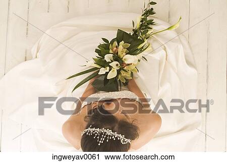 High angle view of a young bride holding a bouquet of flowers View Large Photo Image Stock Image - High angle view of a young bride holding a bouquet of flowers. Fotosearch