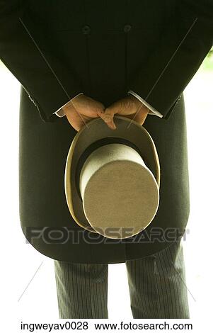 Stock Photo - Rear view of a man holding a hat behind his back. Fotosearch