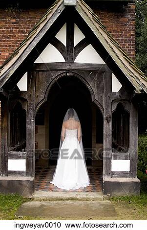 Stock Image - Rear view of a young bride entering a church. Fotosearch