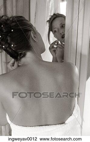 Stock Image - Rear view of a young woman dressing in front of a mirror ( black and white ). Fotosearch