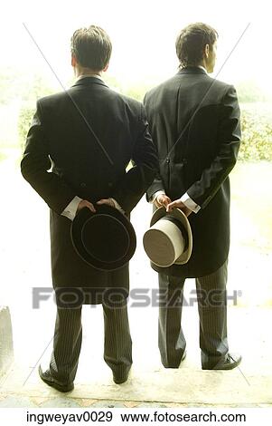 Rear view of two men holding hats behind their backs View Large Photo Image Stock Photo - Rear view of two men holding hats behind their backs. Fotosearch