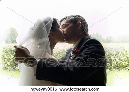 Stock Photography - Side profile of a newly wed couple kissing. Fotosearch