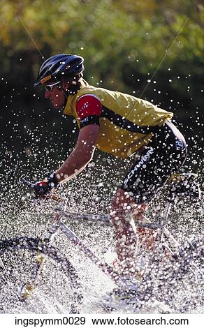 A young man cycling in a stream View Large Photo Image Stock Photo - A young man cycling in a stream. Fotosearch