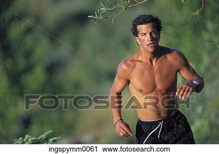 Stock Image - A young man jogging in a forest. Fotosearch