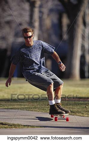Stock Image - A young man skate boarding in a park. Fotosearch