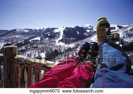 Close-up of two pairs of feet resting on a wooden railing, overlooking a snow covered valley View Large Photo Image Stock Image - Close-up of two pairs of feet resting on a wooden railing, overlooking a snow covered valley. Fotosearch