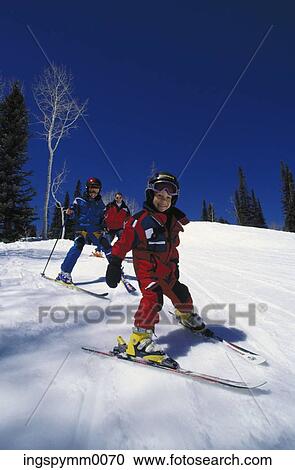 Stock Image - Couple skiing with their daughter on a snowy hill. Fotosearch