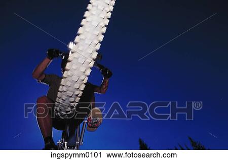 Low angle view of a man on a bicycle View Large Photo Image Stock Image - Low angle view of a man on a bicycle. Fotosearch