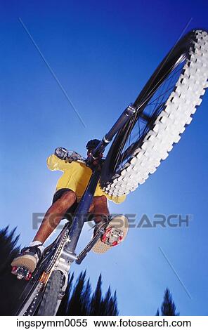 Stock Photography - Low angle view of a man riding a bicycle in midair. Fotosearch