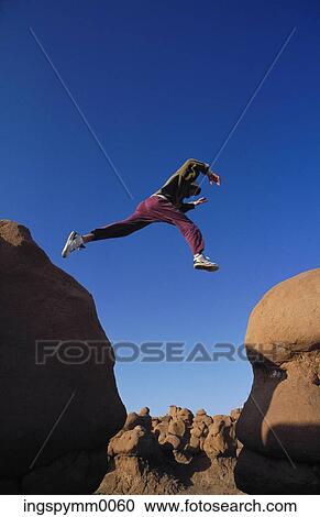 Low angle view of a young man jumping from one rock to another View Large Photo Image Stock Image - Low angle view of a young man jumping from one rock to another. Fotosearch