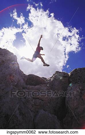Low angle view of a young man jumping on rocks View Large Photo Image Stock Image - Low angle view of a young man jumping on rocks. Fotosearch