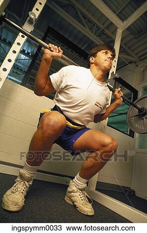 Low angle view of a young man lifting a bar bell in a gym View Large Photo Image Stock Image - Low angle view of a young man lifting a bar bell in a gym. Fotosearch