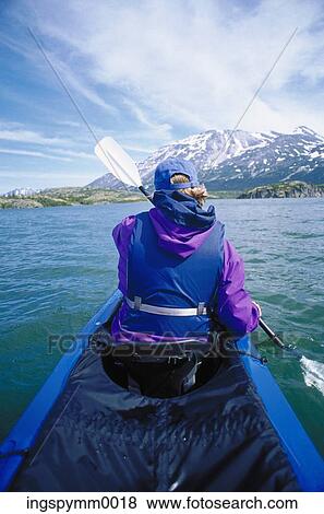 Rear view of a man paddling a canoe on a lake View Large Photo Image Stock Photo - Rear view of a man paddling a canoe on a lake. Fotosearch
