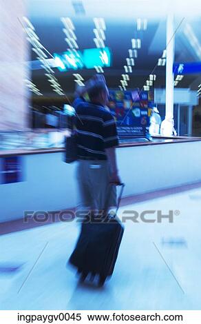 A mid adult man pulling a luggage stroller at an airport View Large Photo Image Stock Photography - A mid adult man pulling a luggage stroller at an airport. Fotosearch