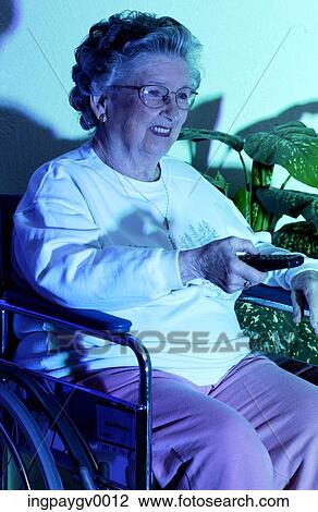 A senior woman holding a remote control, watching TV View Large Photo Image Stock Image - A senior woman holding a remote control, watching TV. Fotosearch