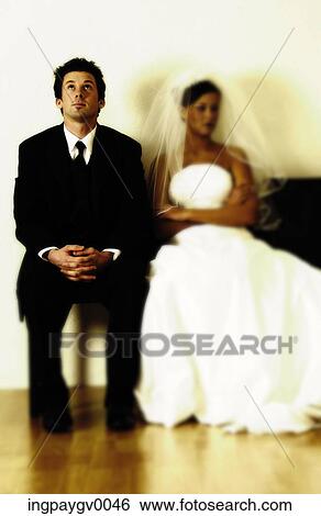 Stock Photograph - A young bride and groom sitting on a couch. Fotosearch