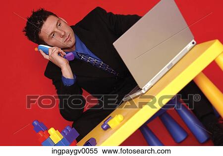 A young businessman talking on a phone, working on a laptop computer View Large Photo Image Stock Photography - A young businessman talking on a phone, working on a laptop computer. Fotosearch