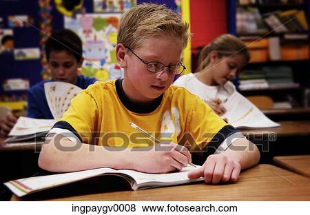 Close-up of a young boy sitting in a classroom View Large Photo Image Stock Photo - Close-up of a young boy sitting in a classroom. Fotosearch