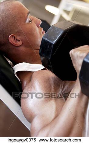 Close-up of a young man lifting bar bells in a gym View Large Photo Image Stock Photography - Close-up of a young man lifting bar bells in a gym. Fotosearch