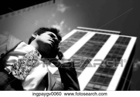 Low angle view of a young businessman talking on a mobile phone View Large Photo Image Stock Image - Low angle view of a young businessman talking on a mobile phone. Fotosearch