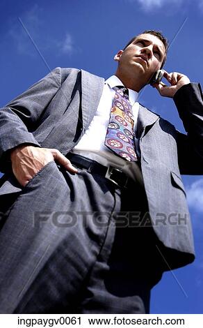 Low angle view of a young businessman talking on a mobile phone View Large Photo Image Stock Image - Low angle view of a young businessman talking on a mobile phone. Fotosearch