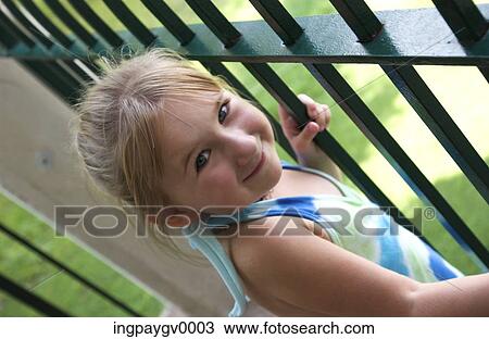Portrait of a young girl standing next to a metal gate, smiling View Large Photo Image Stock Image - Portrait of a young girl standing next to a metal gate, smiling. Fotosearch