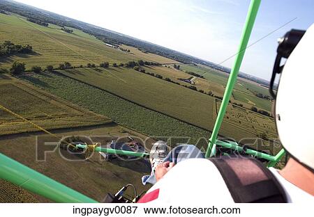 Stock Photo - Rear view of a person sitting on a paraglider. Fotosearch