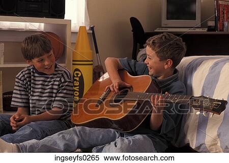 Stock Photography - Boy Playing Guitar For Friend And Laughing. Fotosearch