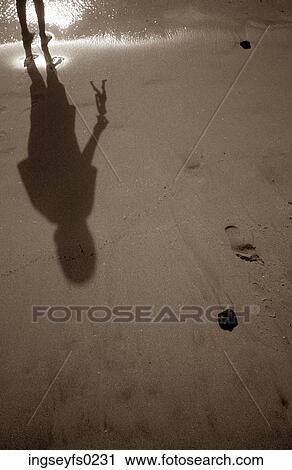 Stock Image - Child Holding Action Figure And Standing On Beach. Fotosearch