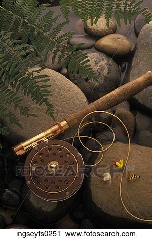 Stock Image - Fishing Reel And Rod Lying On Rocks. Fotosearch